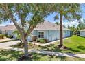 Well-kept single-story home featuring stone accents, beautiful landscaping, and a lush green lawn on a sunny day at 7413 Surrey Wood Ln, Apollo Beach, FL 33572