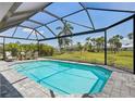 Sparkling pool with screened enclosure, surrounded by a spacious patio and lush landscaping at 7504 Carissa, Punta Gorda, FL 33955