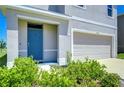 Home exterior with a blue front door, a two-car garage, and landscaping at 10555 Penny Gale Loop, San Antonio, FL 33576
