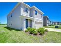 Home with a two-car garage, green lawn, and some landscaping at 10555 Penny Gale Loop, San Antonio, FL 33576