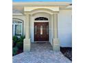 Inviting entryway with a beautiful wood door, decorative sidelights, and classic architectural columns at 1201 Ventana Dr, Sun City Center, FL 33573