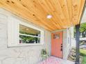 Inviting front porch with a light wood ceiling, a patterned rug, and a vibrant salmon-colored front door at 1221 E Emma St, Tampa, FL 33603