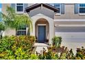 Charming entryway with an arched alcove, blue door, and lush landscaping at 13234 Great Plains Dr, Riverview, FL 33579