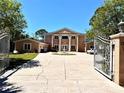 Elegant home showcasing a gated entrance, circular driveway, and a well-manicured lawn at 1516 Bayshore Blvd, Dunedin, FL 34698
