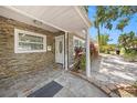 Close-up of the covered front entrance with stone accents, a decorative door, and a tidy landscape at 1557 Robinson N Dr, St Petersburg, FL 33710