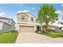 Charming two-story home featuring tan exterior, a two-car garage and landscaped front lawn at 17331 White Mangrove Dr, Wimauma, FL 33598