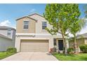 Charming two-story home featuring tan exterior, a two-car garage and landscaped front lawn at 17331 White Mangrove Dr, Wimauma, FL 33598