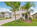 Charming two-story home featuring tan exterior, a two-car garage and landscaped front lawn at 17331 White Mangrove Dr, Wimauma, FL 33598