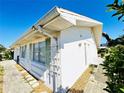 Bright, white exterior showcasing the side of the home, green shutters, and a pathway at 203 Rickenbacker Dr, Sun City Center, FL 33573