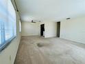 Spacious living room area featuring neutral carpet, a ceiling fan, and multiple windows at 203 Rickenbacker Dr, Sun City Center, FL 33573