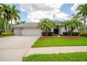 Inviting single-story home features a well-manicured lawn, mature palm trees, and a three-car garage at 211 Royal Bonnet Dr, Apollo Beach, FL 33572