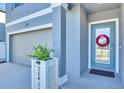 Close-up of the front entrance featuring a wreath on the door, stylish planter, and views of the attached two-car garage at 36454 Flats St, Zephyrhills, FL 33541