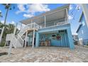Charming waterfront home featuring a outdoor bar area, beautiful landscaping, and a staircase leading to an upper deck at 4039 Casa Ct, Hernando Beach, FL 34607