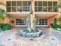 Elegant condo building entrance with a beautiful dolphin statue, tile walkway, and lush tropical plants at 4516 Seagull Dr # 903, New Port Richey, FL 34652