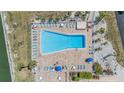 Aerial view of a resort-style pool area with ample lounge seating, surrounded by lush landscaping and serene waterways at 9 Forbes Pl # 205, Dunedin, FL 34698