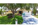 Charming home featuring a well-manicured lawn, mature tree, and inviting front entrance with chairs at 907 Golf Island Dr, Apollo Beach, FL 33572