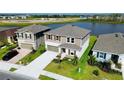 Aerial view of a two-story home with neutral siding and shutters, two-car garage, and landscaping near a lake at 9567 Sandy Bluffs Cir, Parrish, FL 34219