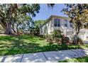 Side view of a two-story townhouse with well-maintained lawn, landscaping and attached one car garage at 9814 Ashburn Lake Dr, Tampa, FL 33610