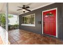 The front porch of the home features a ceiling fan and a vibrant red front door at 1222 E Powhatan Ave, Tampa, FL 33604