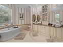 Elegant bathroom with soaking tub, dual vanities, and stylish striped wallpaper at 15053 Peace Blvd, Spring Hill, FL 34610