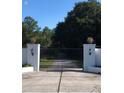 Elegant gated entrance with white pillars and decorative lanterns, leading to a private driveway at 22129 Carson Dr, Land O Lakes, FL 34639