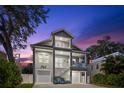 Dusk view of a two-story home with balconies and dual garages, illuminated against a colorful sky at 322 Ontario Ave, Crystal Beach, FL 34681