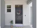 Elegant entryway boasting a black front door with decorative wreath, welcome mat and small window at 32978 Tulip Petal Ln, Wesley Chapel, FL 33545