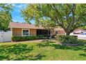 Beautiful single-story house surrounded by a well-manicured lawn, mature trees, and verdant shrubbery at 506 Spring Tree Ct, Tarpon Springs, FL 34689