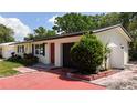 Cozy single-story home featuring a bright red door, and lush landscaping at 809 Scotland St, Dunedin, FL 34698