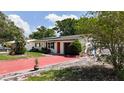 Charming single-story home with bright red driveway, lush landscaping, and a cozy exterior at 809 Scotland St, Dunedin, FL 34698