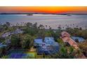 Breathtaking sunset aerial view featuring waterfront homes, lush greenery, and a glimpse of a tennis court at 147 & 139 Edgewater Dr, Dunedin, FL 34698