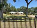 Lovely home surrounded by mature trees, a green lawn, and a decorative iron fence at 1504 Swilley Rd, Plant City, FL 33567