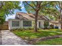 Charming home featuring a well-manicured lawn, beautiful trees, and classic architecture with eye-catching blue shutters at 1905 Mckinley St, Clearwater, FL 33765