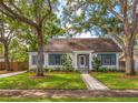 Charming home featuring a well-manicured lawn, beautiful trees, and classic architecture with eye-catching blue shutters at 1905 Mckinley St, Clearwater, FL 33765
