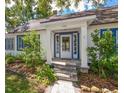 Close-up of the welcoming front porch with a glass door, white pillars, and stone steps, framed by lovely landscaping at 1905 Mckinley St, Clearwater, FL 33765