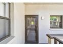 Exterior view of unit 203, featuring a neutral-colored wall, a small window and the front door at 2650 Countryside Blvd # C203, Clearwater, FL 33761