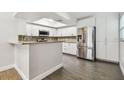 Open kitchen with granite countertops, stainless steel refrigerator, white cabinets, and hardwood-style floors at 2650 Countryside Blvd # C203, Clearwater, FL 33761