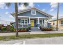 Charming home with blue siding, bright yellow door, and landscaped front yard under a partly cloudy sky at 2704 W Main St, Tampa, FL 33607