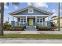 Inviting home boasting a spacious front porch, blue siding, white trim, and colorful landscaping at 2704 W Main St, Tampa, FL 33607