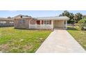 Well-kept single-Gathering home featuring a tidy lawn and a driveway leading to the carport at 6556 S West Shore Cir, Tampa, FL 33616