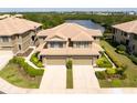 An aerial view of an elegant townhome with a tile roof surrounded by verdant landscaping and a tranquil pond at 7657 Caponata Blvd, Seminole, FL 33777