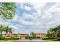 Welcoming gated community entrance with lush tropical landscaping and beautiful residential buildings at 7657 Caponata Blvd, Seminole, FL 33777