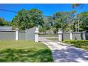 Gated driveway entrance with lush green lawn and a well-maintained fence for added security at 1120 Country Ln, Lutz, FL 33558