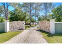 Impressive gated driveway entrance with stone accents and a well-maintained lawn at 1120 Country Ln, Lutz, FL 33558