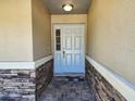 Inviting front entrance featuring a light blue front door, stone accents, and a decorative welcome mat at 13400 Old Florida Cir, Hudson, FL 34669
