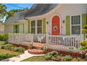 Charming home boasting a well-maintained lawn, quaint front porch, and a vibrant orange front door with decorative wreath at 1603 S Arrawana Ave, Tampa, FL 33629