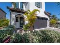 Charming home features a gray garage door, black framed windows, and tropical landscaping at 19554 Roseate Dr, Lutz, FL 33558