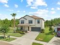 Charming two-story house featuring a landscaped front yard, covered porch, and attached two-car garage at 21383 Southern Charm Dr, Land O Lakes, FL 34637