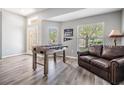Bright room features a foosball table, wood-look floors, and a comfortable leather couch by window at 25324 Lexington Oaks Blvd, Wesley Chapel, FL 33544