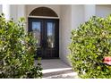 Close-up of the elegant double front doors framed by lush greenery, offering a grand entrance to the home at 30247 Fairway Dr, Wesley Chapel, FL 33543
